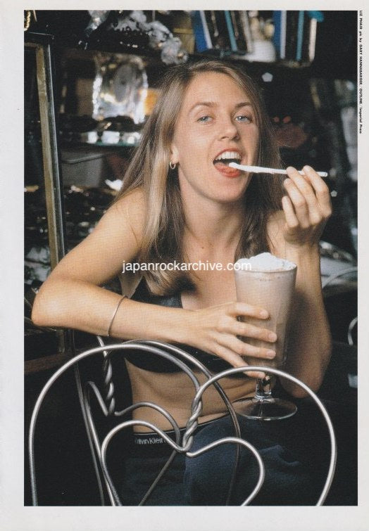 Liz Phair enjoying a dessert in a casual setting with a vintage feel.