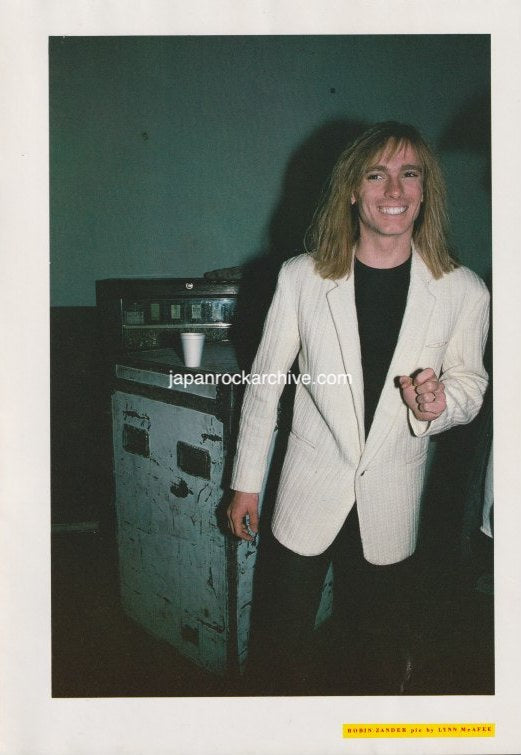 Robin Zander of Cheap Trick in a light-colored blazer standing next to a touring road case