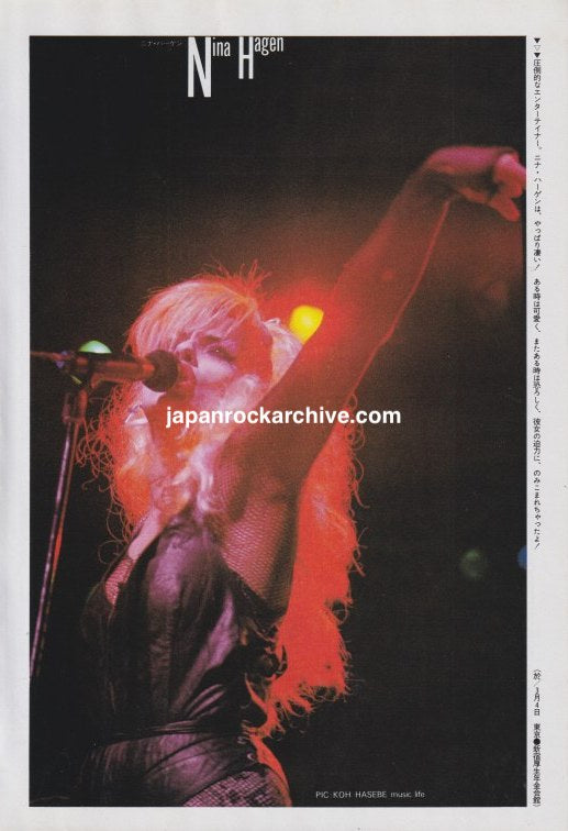 Nina Hagen singing into a microphone with one arm raised under red stage lighting, May 1985 Japanese magazine color pinup.
